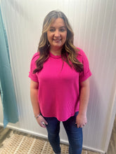 Load image into Gallery viewer, Woman wearing a pink top and blue jeans standing against a white wall.