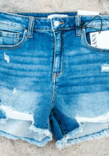 Load image into Gallery viewer, dark blue denim shorts with frayed edges on a concrete surface