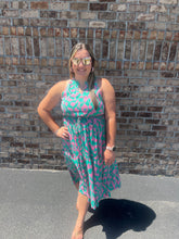 Load image into Gallery viewer, Woman wearing a pink and green dress standing against a brick wall.
