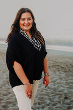 Load image into Gallery viewer, Woman standing on a beach wearing a black top trimmed in leopard around neck and sand beige pants