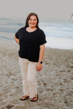 Load image into Gallery viewer, Woman standing on a beach wearing a black shirt and sand beige pants.