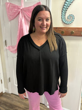 Load image into Gallery viewer, Woman wearing a black top and pink pants standing indoors with decorative elements in the background.