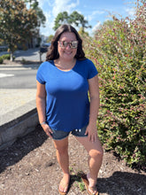 Load image into Gallery viewer, Woman wearing a blue shirt and sunglasses standing outdoors on a sunny day.