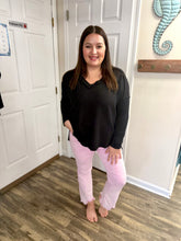 Load image into Gallery viewer, Woman wearing a black top and lilac pants standing in a room with white walls and a wooden floor.