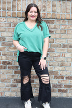 Load image into Gallery viewer, Woman wearing a green top and black pants on a brick pavement