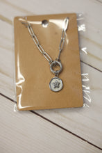 Load image into Gallery viewer, Silver necklace with a starfish charm on a brown card, placed on a wooden surface.