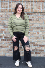 Load image into Gallery viewer, Woman wearing a green striped shirt and black pants against a brick wall