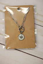Load image into Gallery viewer, Silver necklace with a shell pendant on a brown card, wrapped in clear plastic, on a wooden surface.