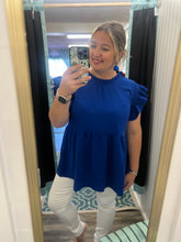 Load image into Gallery viewer, Woman wearing a blue top and white pants in front of a mirror.