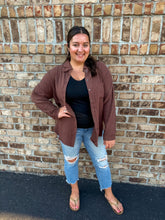 Load image into Gallery viewer, Woman wearing a brown gauze long sleeve shirt, black tank, and blue jeans standing against a brick wall.