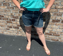 Load image into Gallery viewer, Person wearing a turquoise top and denim shorts standing against a brick wall.