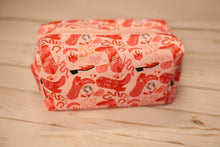 Load image into Gallery viewer, Red and pink cowboy print cosmetic pouch  on a wooden surface
