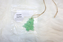 Load image into Gallery viewer, Green tree-shaped car freshie ornament with a label on a white background scented sweater weather
